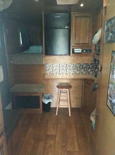 the interior of an rv with wood flooring and wooden cabinets, including a stool