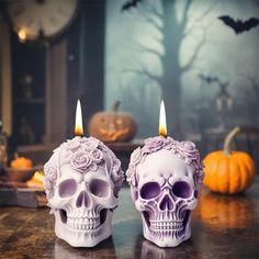 two skulls with candles sitting on a table