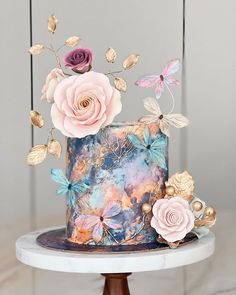 there is a cake decorated with flowers and butterflies on the top of the cake stand