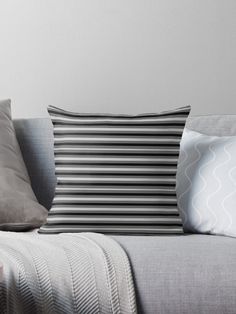 a blue and white striped pillow sitting on top of a gray couch next to pillows