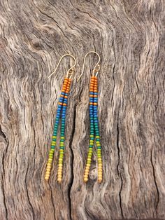 two pairs of multicolored beaded earrings sitting on top of a piece of wood