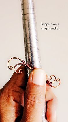 a person holding a metal object in their hand with the words shape it on a ring handle