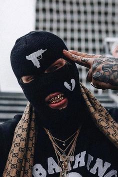 a man with tattoos on his face wearing a black mask and scarf over his head