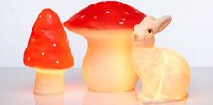 a rabbit figurine sitting in front of two mushroom shaped lights on a table