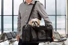 a man holding a black bag with a dog in it