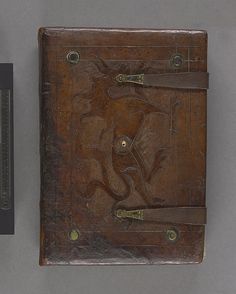 an old leather book sitting on top of a table next to a thermometer