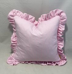 a pink and white striped pillow with ruffled edges