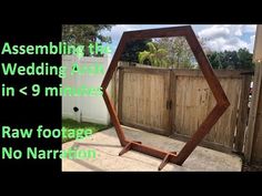 a large wooden mirror sitting on top of a cement floor in front of a fence