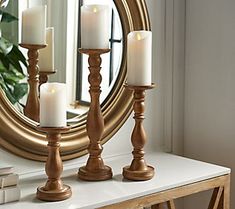 three candles are lit on a table in front of a mirror with a gold frame