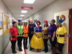 a group of people dressed up in costumes posing for a photo on a school hallway