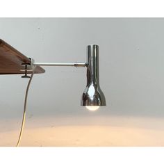 a wall mounted light with a wooden arm and metal fixture on it's side