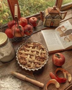 an apple pie sitting on top of a wooden table next to apples and other fruit