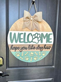 a welcome sign hanging on the front door to a dog's kennel with a bow