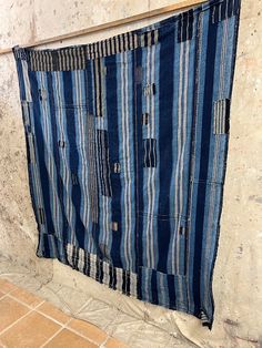 a blue and white striped cloth hanging on a wall next to a tile floor with a wooden frame