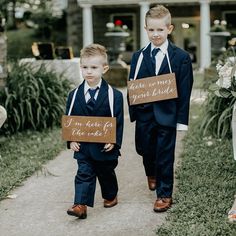 two young boys wearing suits and ties holding signs