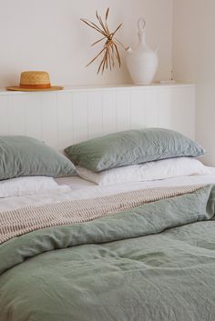 a bed with two pillows on top of it and a vase next to the headboard