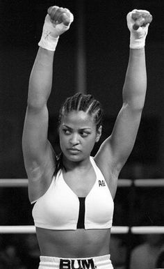 a woman with her arms up in the air while standing on top of a wrestling ring