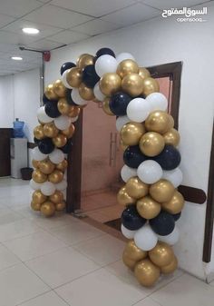 an arch made out of balloons is shown in the middle of a room with white and gold