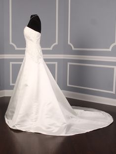 a wedding dress is displayed on a mannequin in front of a blue wall