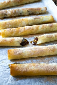 breadsticks with raisins and other toppings are lined up on a baking sheet