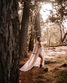 a woman in a dress is walking through the woods