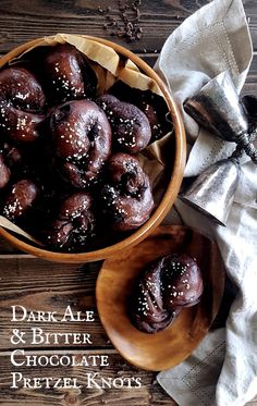 two wooden bowls filled with chocolate covered donuts on top of a table next to napkins