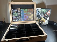 an open wooden box on top of a table filled with comic books and cd's