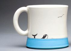 a white and blue coffee mug with two birds on the top, sitting in front of a gray background