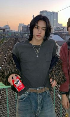 two young men standing next to each other on a bridge with buildings in the background