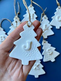 a hand holding a white ceramic christmas tree ornament