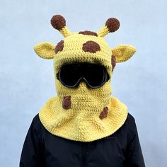 a person wearing a knitted giraffe mask with sunglasses on it's face