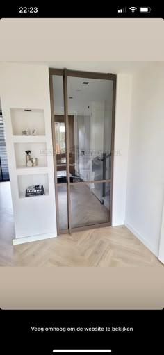 an open door in the middle of a room with white walls and wood flooring