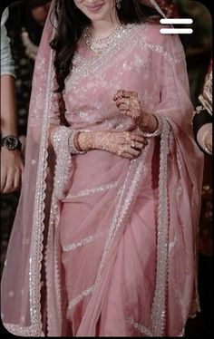 a woman in a pink sari with white and silver work on her hands, smiling at the camera