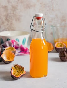 a glass bottle filled with orange juice next to some fruit