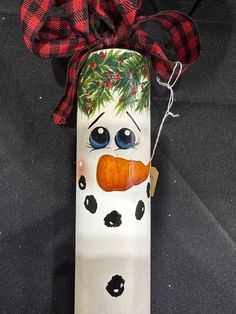 a painted snowman with a red bow on it's head