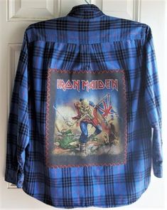 the back of a blue shirt with an image of iron maiden on it, hanging from a door