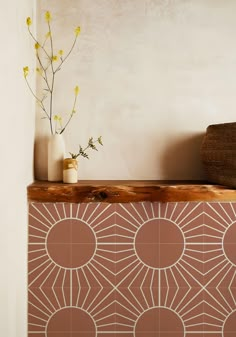 a vase sitting on top of a wooden shelf next to a wall with flowers in it