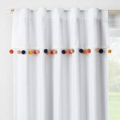 a white curtain with pom poms hanging from it's rodulage