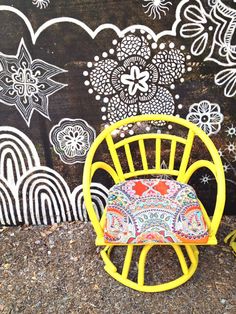 a yellow chair sitting in front of a black and white wall with designs on it