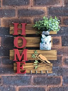 a wooden sign that says home on it next to a potted plant and spoon