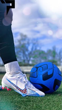 a blue soccer ball sitting on top of a field next to a person's legs