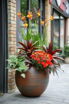 a large planter filled with lots of flowers sitting on the side of a building