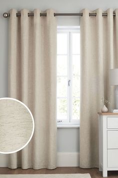 a living room with white furniture and beige drapes on the windowsill, along with an area rug