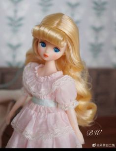 a doll with long blonde hair wearing a pink dress