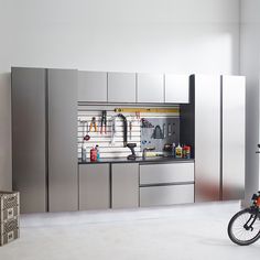 a bike parked in front of a kitchen with stainless steel cabinets and tools on the wall