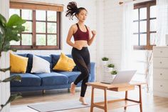 a woman running in her living room with a laptop on the coffee table next to her