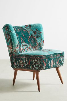 an upholstered green chair with wooden legs