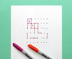 two markers are sitting on top of a piece of paper that is drawn with squares and dots