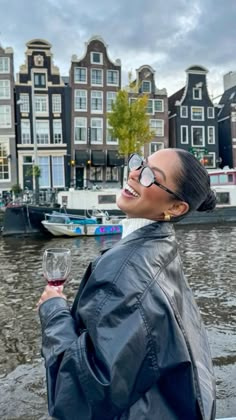 a woman standing on a boat holding a wine glass in her hand and looking up at the sky