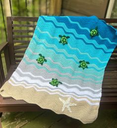 a crocheted blanket on a bench with sea turtles in the waves and starfish